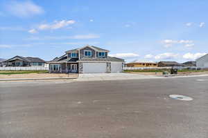 View of front of house with a residential view, stone siding, a garage, a porch, and concrete driveway