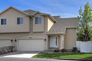 Traditional-style house featuring roof with shingles, stucco siding, concrete driveway, and a garage