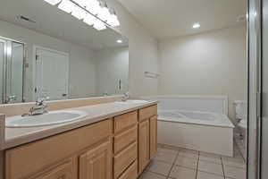Full bathroom with double vanity, a garden tub, light tile patterned flooring, and recessed lighting