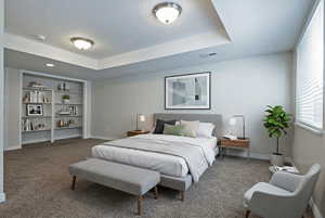 Bedroom with a raised ceiling and carpet
