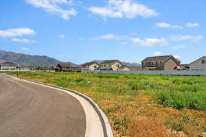 View of asphalt road featuring curbs, a mountain view, and a residential view