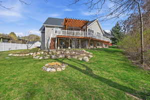 Rear view of property featuring a fire pit, a deck, a pergola, a patio, and roof with shingles