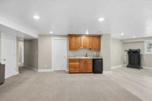 Indoor wet bar featuring wood finish cabinetry, black fridge, recessed lighting, and light carpet