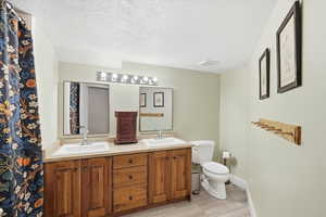 Bathroom featuring double vanity and a textured ceiling