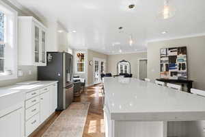Kitchen featuring white cabinetry, light stone counters, a spacious island, a breakfast bar area, and pendant lighting