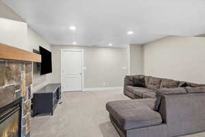 Living room featuring light colored carpet, a stone fireplace, and recessed lighting