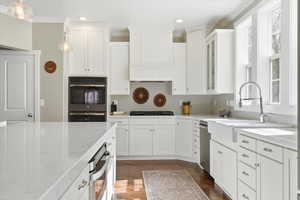 Kitchen with white cabinetry, stainless steel appliances, pendant lighting, and ornamental molding
