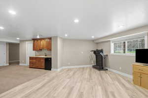 Exercise area with recessed lighting, light wood-style floors, and bar with sink
