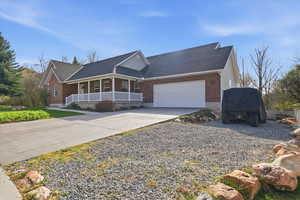 View of front of property with covered porch, roof with shingles, concrete driveway, and brick siding