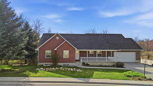 Ranch-style home with covered porch, a front yard, brick siding, and driveway