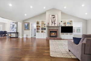 Living area with dark wood-style floors, recessed lighting, and a brick fireplace