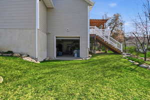 Rear view of property with a garage, a patio, a pergola, and a yard