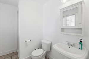 Half bathroom with toilet and light tile patterned flooring