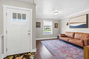 Foyer with crown molding, dark wood finished floors, and a textured ceiling