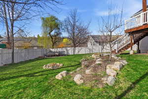 Fenced backyard with a trampoline, a fire pit, and a wooden deck