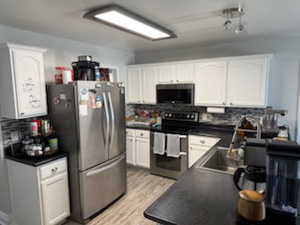 Kitchen with dark countertops, white cabinetry, and stainless steel appliances