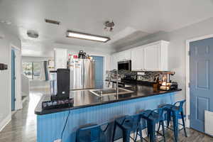 Kitchen with a breakfast bar, a peninsula, stainless steel appliances, decorative backsplash, and white cabinetry