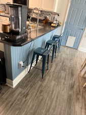Kitchen featuring decorative backsplash, dark countertops, wood finished floors, and a peninsula