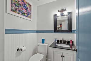 Half bath with vanity and a wainscoted wall