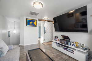 Living room featuring a barn door and dark wood finished floors