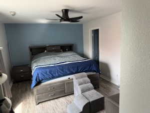 Bedroom featuring a ceiling fan, wood finished floors, and a textured wall