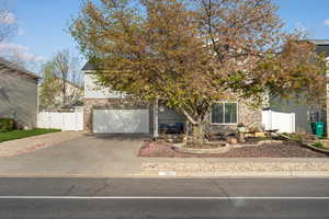 Obstructed view of property featuring a gate, brick siding, driveway, an attached garage, and covered porch