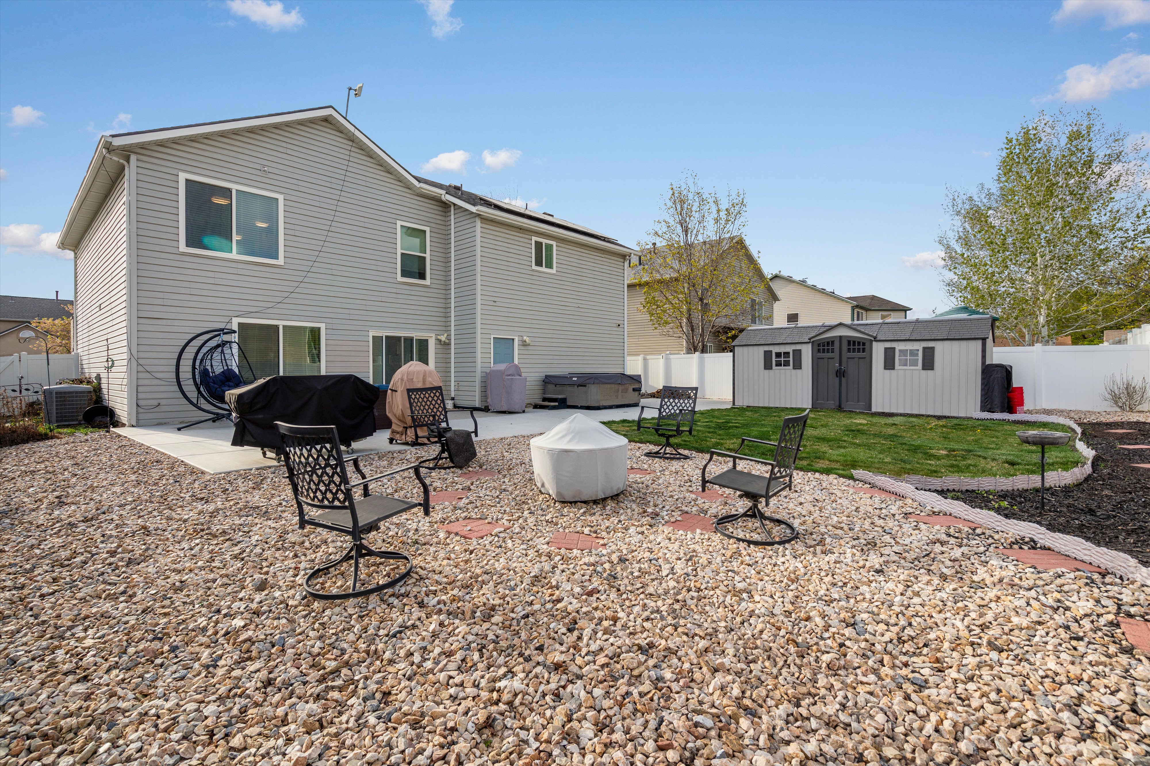Rear view of house with a patio area, a fenced backyard, a storage unit, a hot tub, and an outdoor fire pit