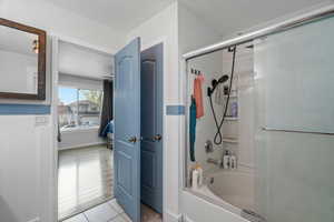 Bathroom featuring combined bath / shower with glass door and light tile patterned floors