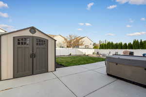 Fenced backyard featuring a patio area, a shed, and a hot tub