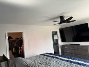 Bedroom with ensuite bathroom, a spacious closet, and ceiling fan