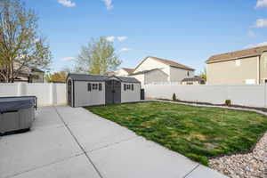 Fenced backyard with a storage shed, a residential view, and a hot tub