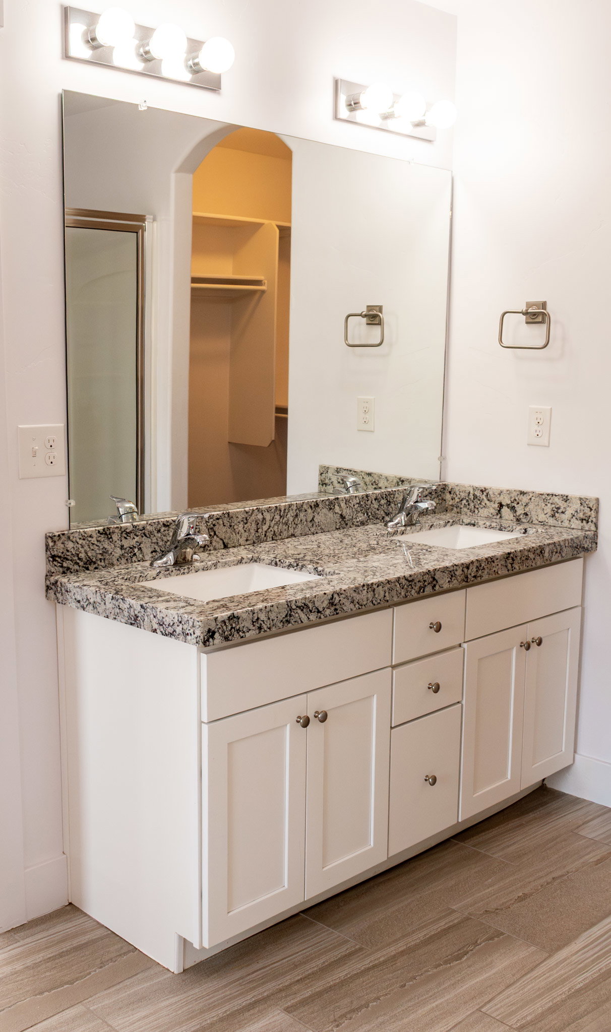 Master Bathroom with double vanity, light wood-style flooring, and a stall shower