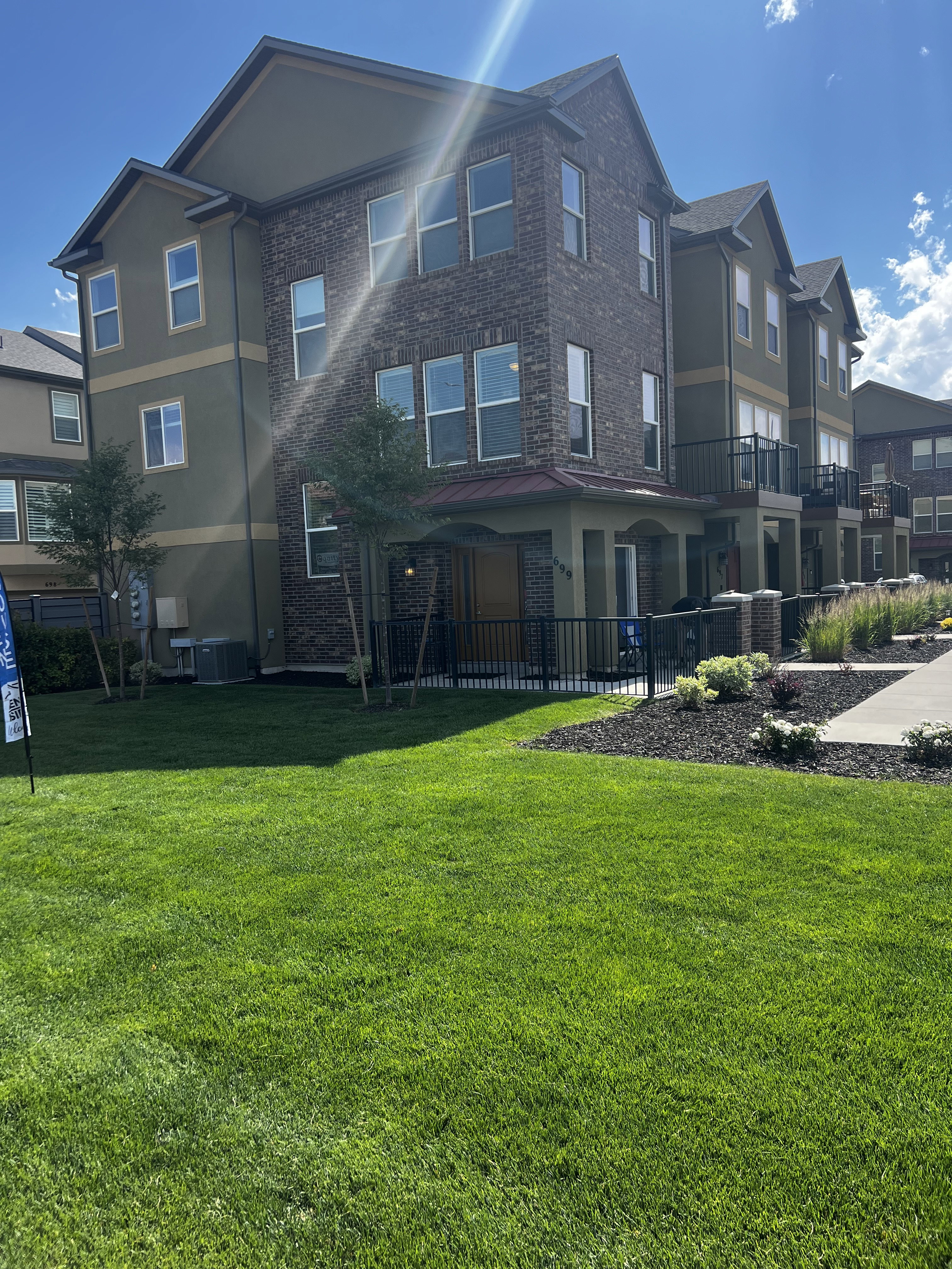 Multi-story townhome featuring brick and stucco exterior, multiple windows, and a covered entry