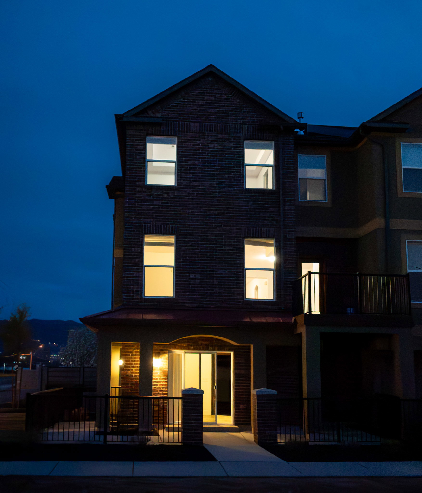 Back of house at night with a fenced front yard and a balcony
