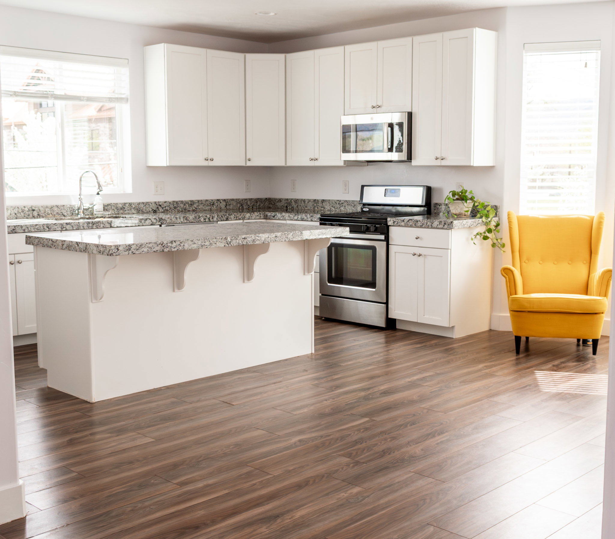 Kitchen featuring stainless steel appliances, a kitchen breakfast bar, white cabinets, and dark wood-style floors