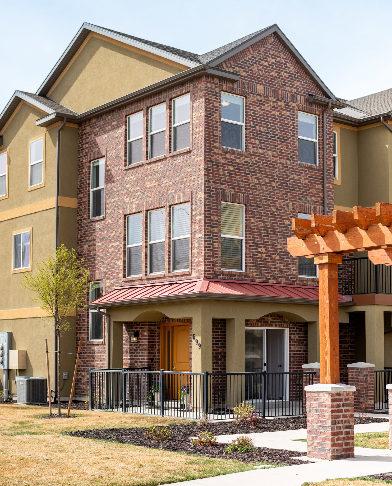 View of front of property featuring brick siding, stucco siding, a pergola, and a standing seam roof