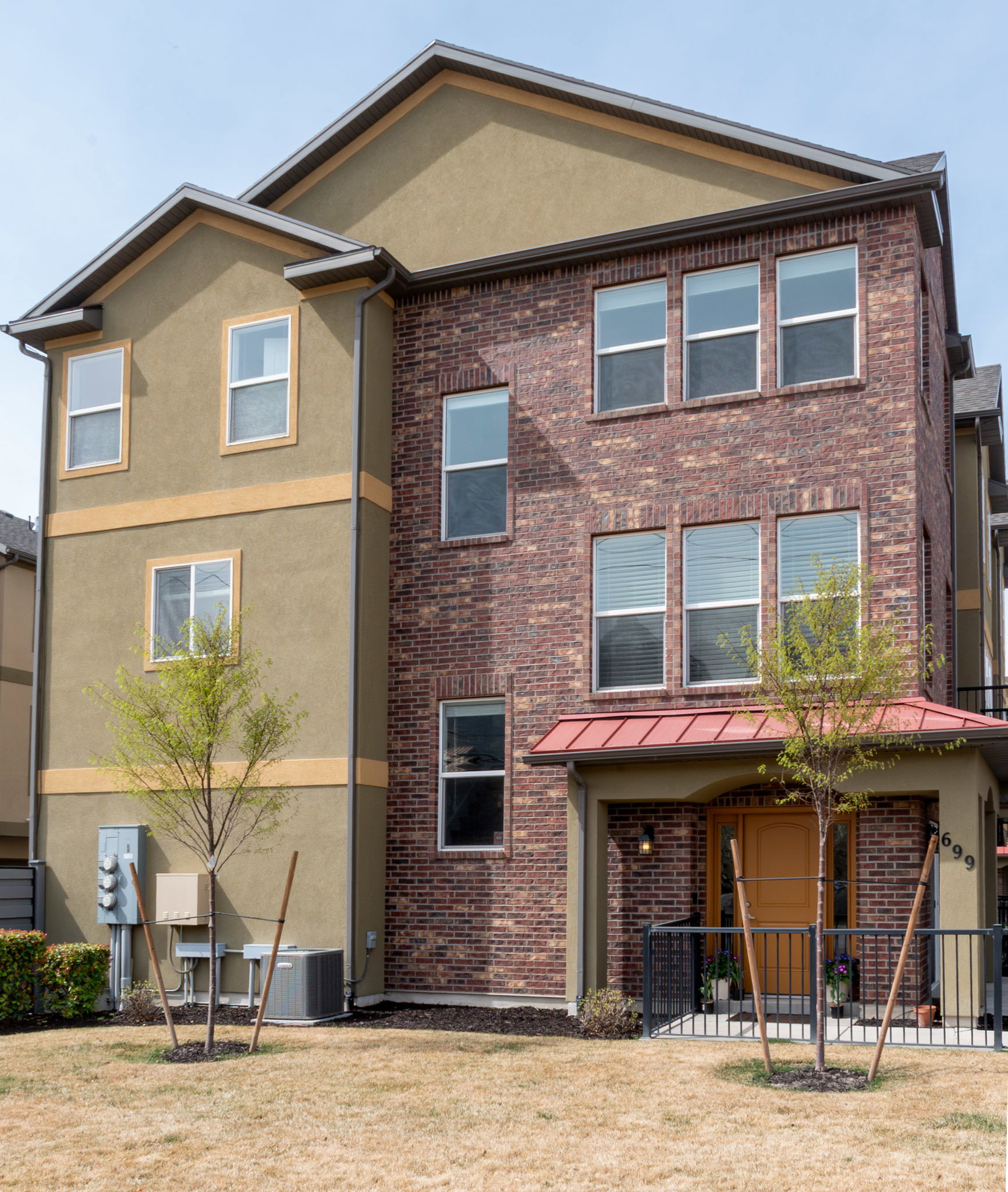 Traditional-style house featuring brick siding, stucco siding, a patio area, and a front yard