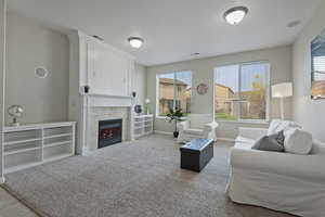 Living area with a fireplace and light carpet