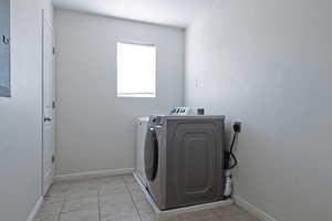 Laundry room featuring light tile patterned floors, washing machine and dryer, and electric panel