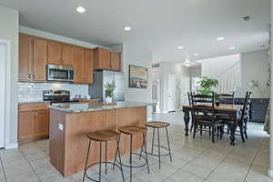 Kitchen with light stone countertops, wood finish cabinets, a kitchen island, stainless steel appliances, and recessed lighting