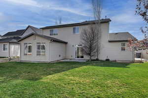 Back of property with roof mounted solar panels, a patio area, a yard, and roof with shingles