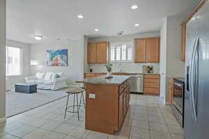 Kitchen featuring light stone countertops, stainless steel appliances, open floor plan, a breakfast bar, and a center island