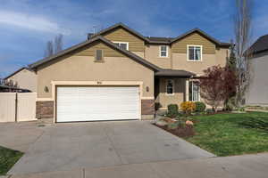 Traditional-style home featuring stone siding, concrete driveway, an attached garage, and stucco siding