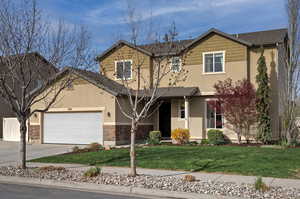 Traditional-style house with driveway, a front lawn, stucco siding, and stone siding
