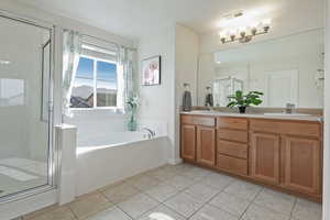Bathroom with double vanity, a garden tub, a shower stall, and light tile patterned floors