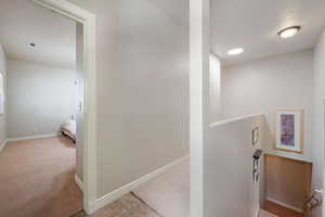 Hall featuring light colored carpet and an upstairs landing