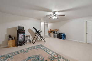 Exercise room with a ceiling fan and carpet floors