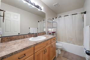 Bathroom featuring vanity, shower / bath combination with curtain, and light tile patterned floors