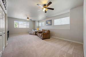 Living area featuring a ceiling fan and light carpet