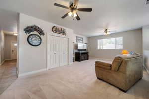 Living room with ceiling fan and light carpet